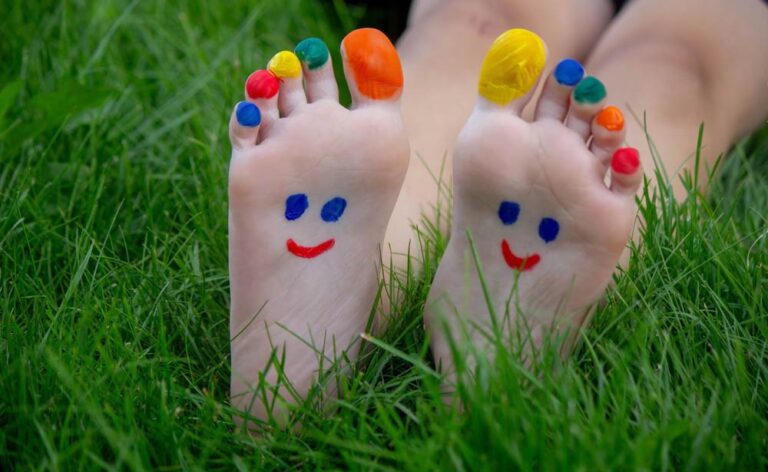 Kinderfuß-Orthopäde. Kinderfüße mit einem bunten, aufgemalten Gesicht